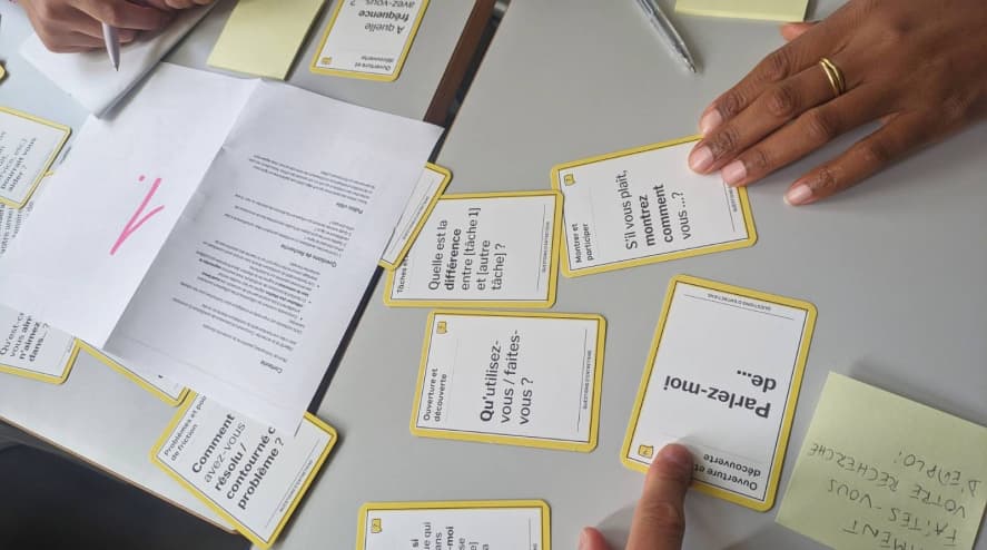 Atelier de création de guide d'entretien : des cartes sont sur la table avec un post-it pour la question complète et un guide d'entretien papier 